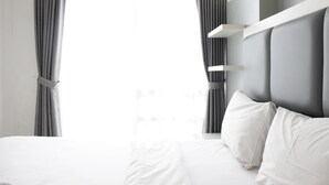 A modern hotel room with a large bed, grey curtains, and a white headboard. - Elegant 1Br Apartment Landmark Residence Bandung Near 23 Paskal Shopping Center (Bandung)