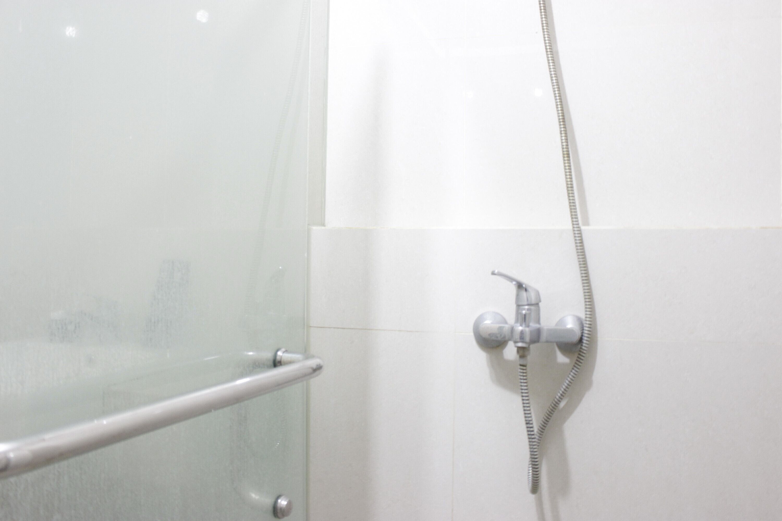 A shower area with a glass door and a handheld showerhead.