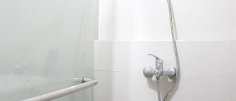 A shower area with a glass door and a handheld showerhead.
