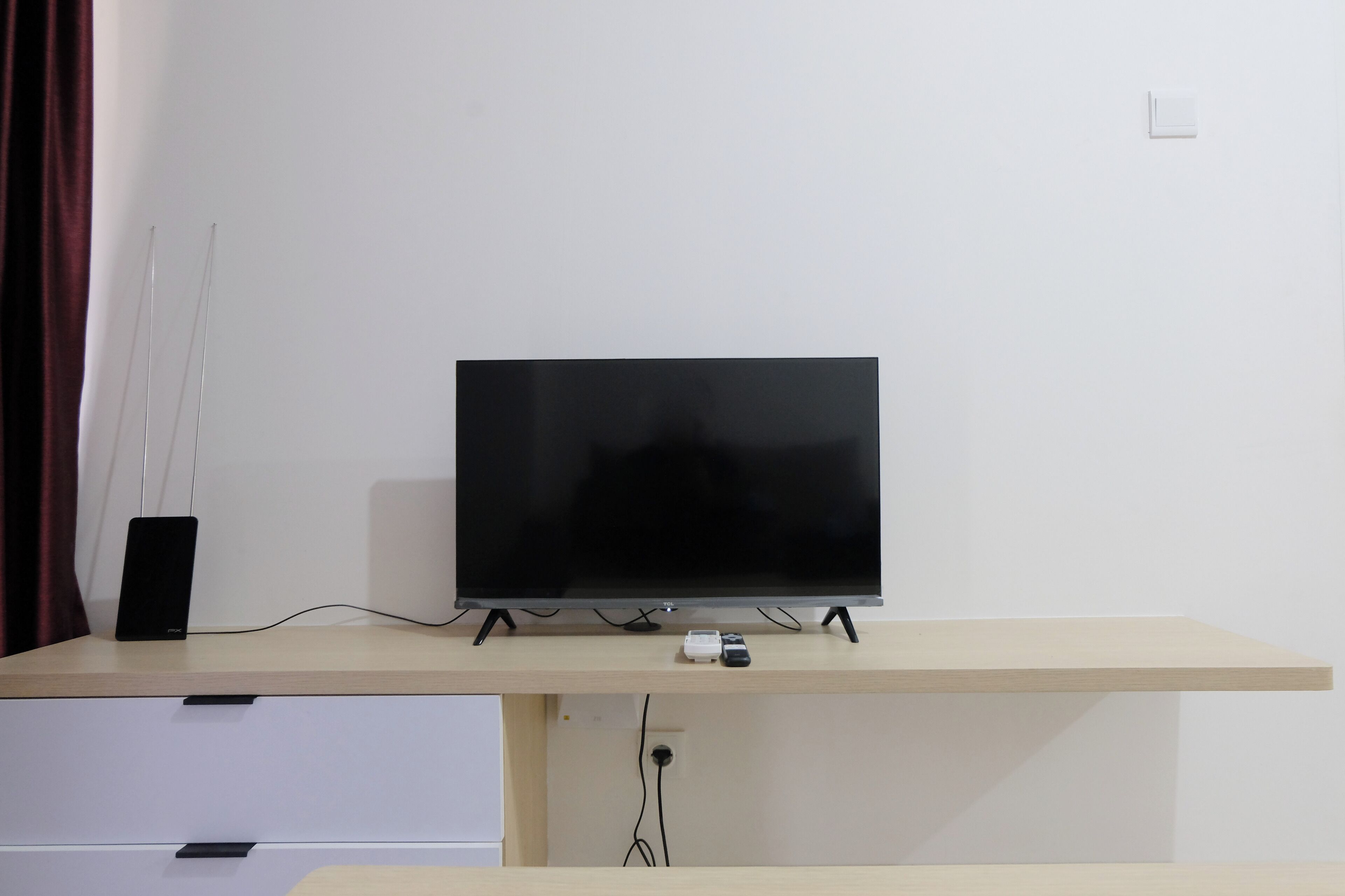 Un televisor de pantalla plana sobre un mueble de madera con un cajón debajo.