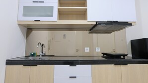 A modern kitchen with a black countertop, white cabinets, a microwave, and a built-in oven. - Good Deal 1Br Apartment Landmark Residence Bandung (Bandung)