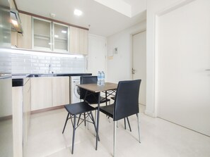 Cocina compacta con comedor, que incluye una mesa con sillas, lavadora y dispensador de agua.