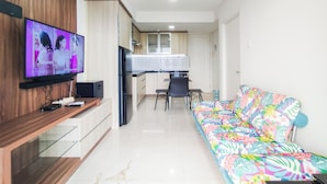 A modern living room with a flat-screen TV, a sofa, a dining area, and a kitchen.