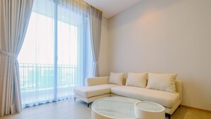 Un soggiorno moderno con un divano color beige, un tavolino rotondo e tende leggere.
