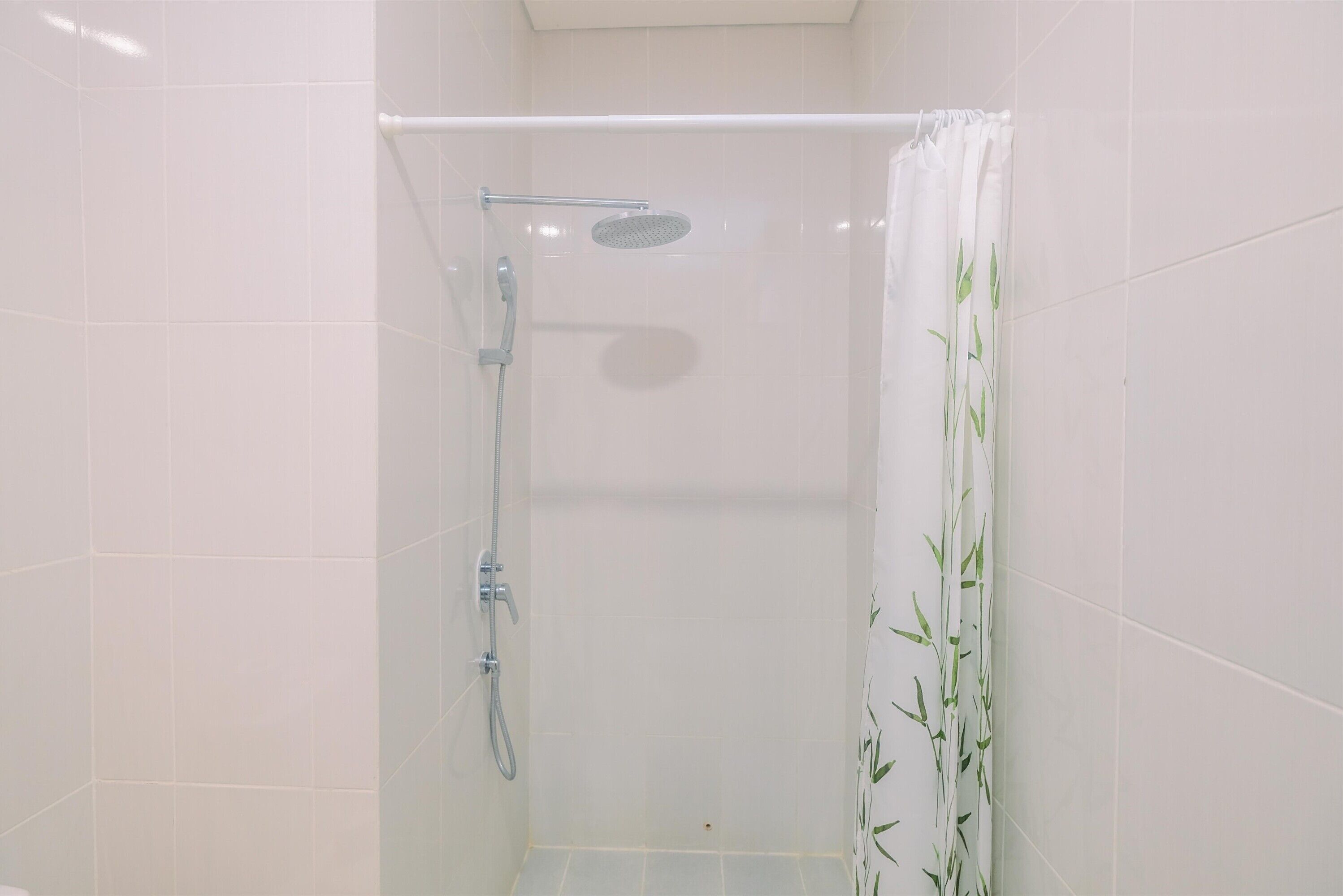 A small, enclosed shower area with a handheld showerhead and a wall-mounted control.