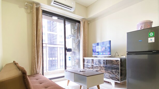 Una sala moderna con un sofá, una mesita, un televisor y un refrigerador.