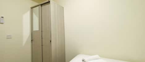 A bedroom with a bed, a wardrobe, and a wall-mounted light switch.