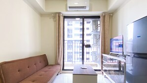 Una sala de estar moderna con un sofá, una mesita, un televisor de pantalla plana y un refrigerador.