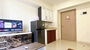 Una cocina moderna con horno integrado, refrigerador y televisión mostrando una película.