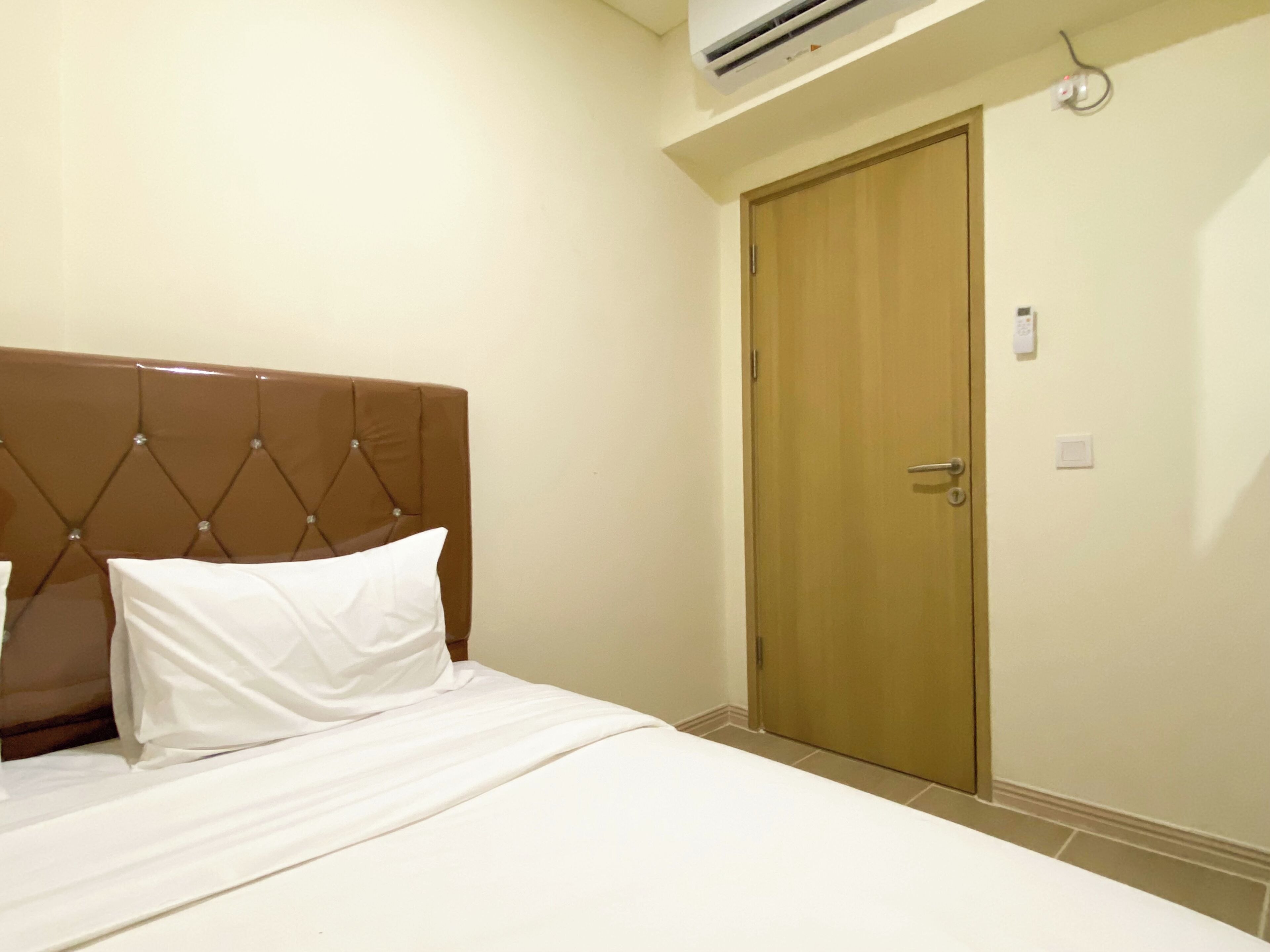 Una habitación de hotel con una cama, una puerta de madera y un equipo de aire acondicionado.