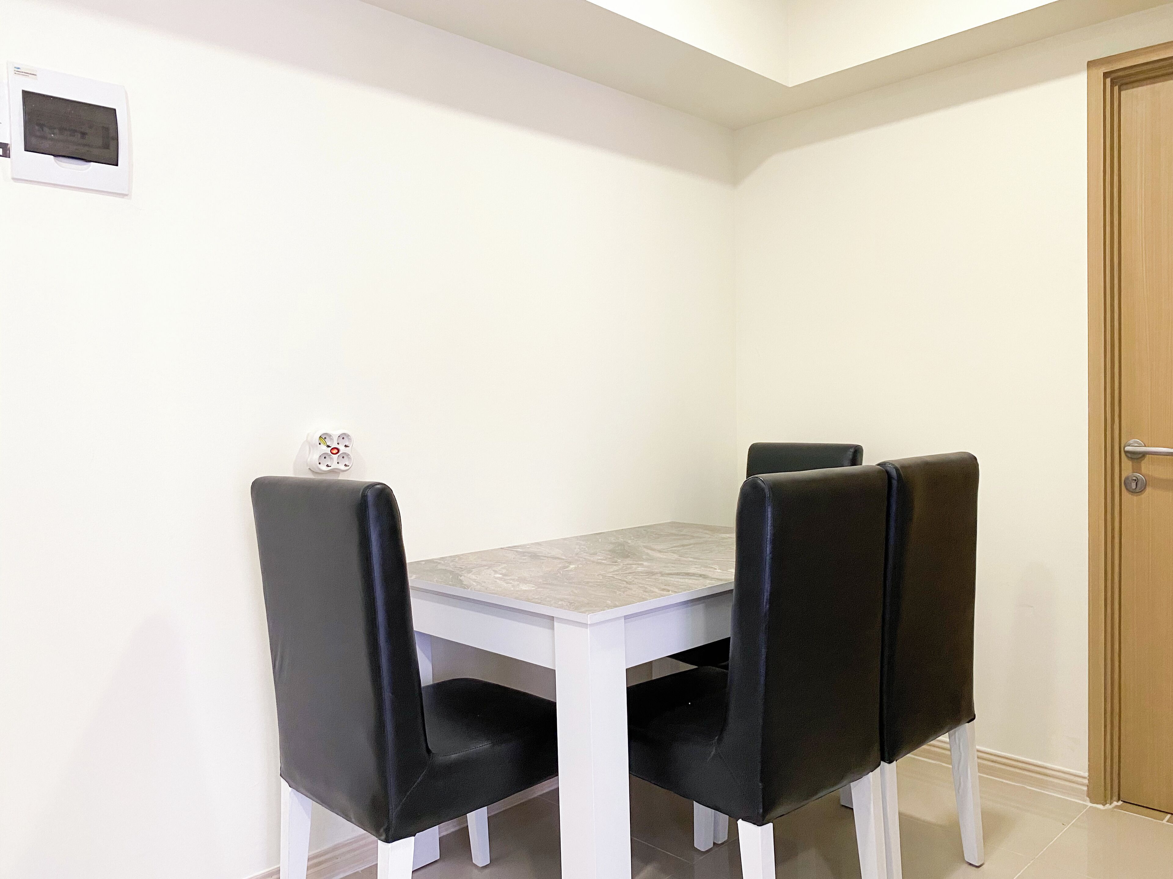 Un coin repas avec une table blanche et quatre chaises noires.
