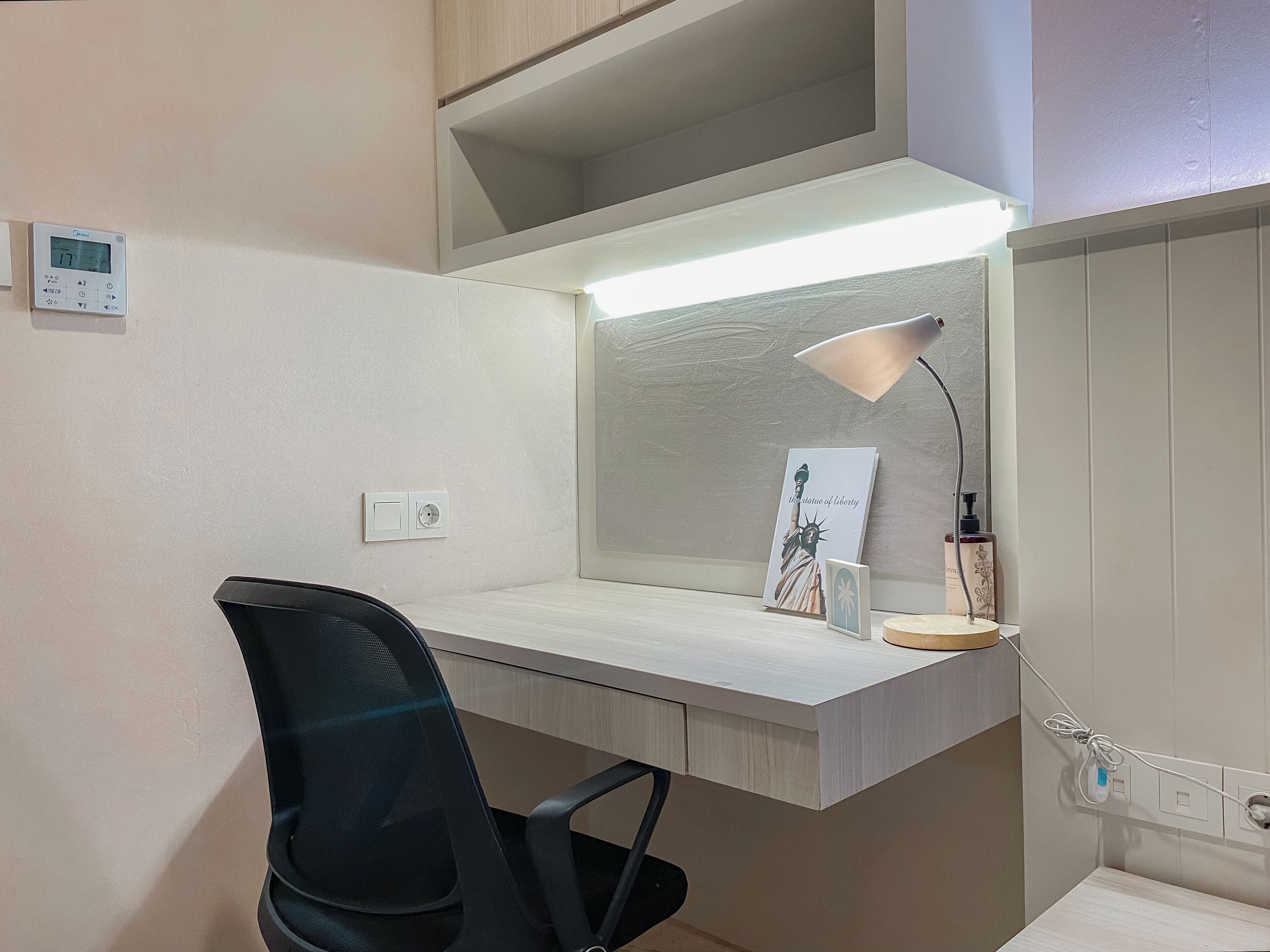Un espacio de oficina moderno con escritorio, silla y lámpara de pared.