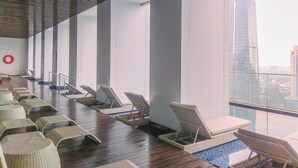 A modern indoor pool area with lounge chairs and a view of a cityscape.