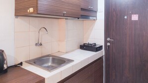 Eine Küche mit einem Edelstahlspülbecken, Holzschränken und einem schwarzen Gerät auf der Arbeitsplatte.