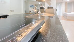 Eine moderne Küche mit einem schwarzen Induktionskochfeld, einer Edelstahl-Spüle und einem eingebauten Backofen.