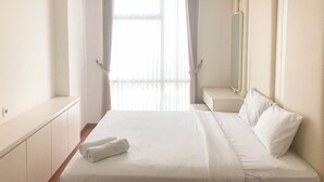 Een hotelkamer met een groot bed, een nachtkastje, een spiegel en een raam met gordijnen.