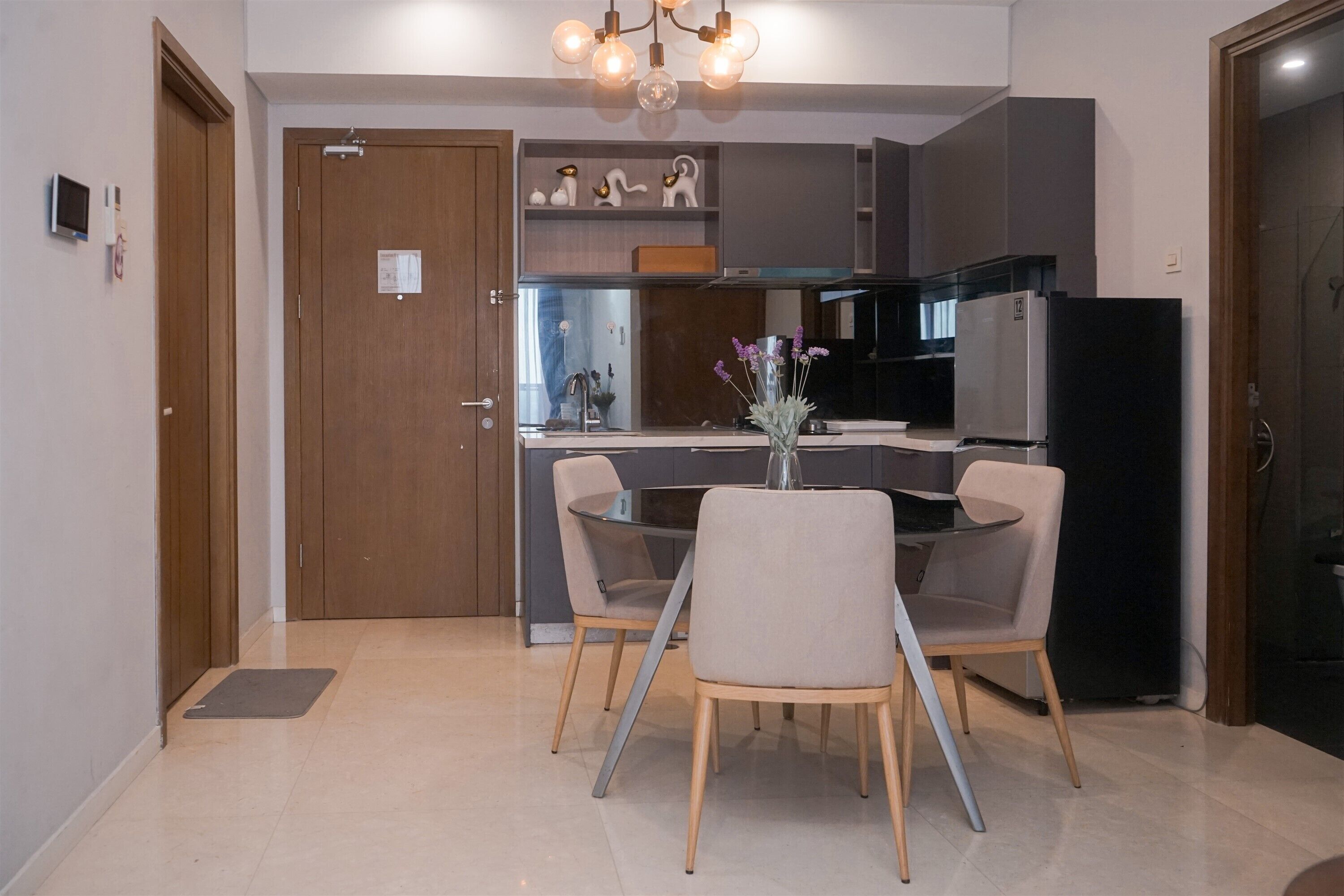 A modern kitchen with a dining area, featuring a central island, dark cabinetry, and a chandelier.