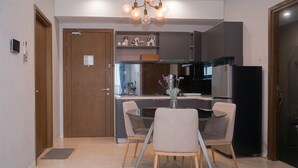 Una cucina moderna con zona pranzo, caratterizzata da un'isola centrale, mobili scuri e un lampadario.