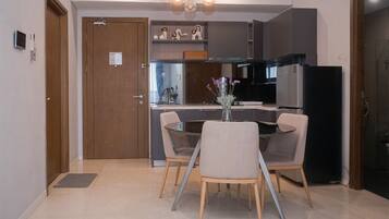 A modern kitchen with a dining area, featuring a central island, dark cabinetry, and a chandelier.