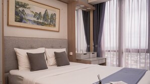 Un letto rifatto con cuscini, un comodino con una lampada e un quadro appeso al muro.