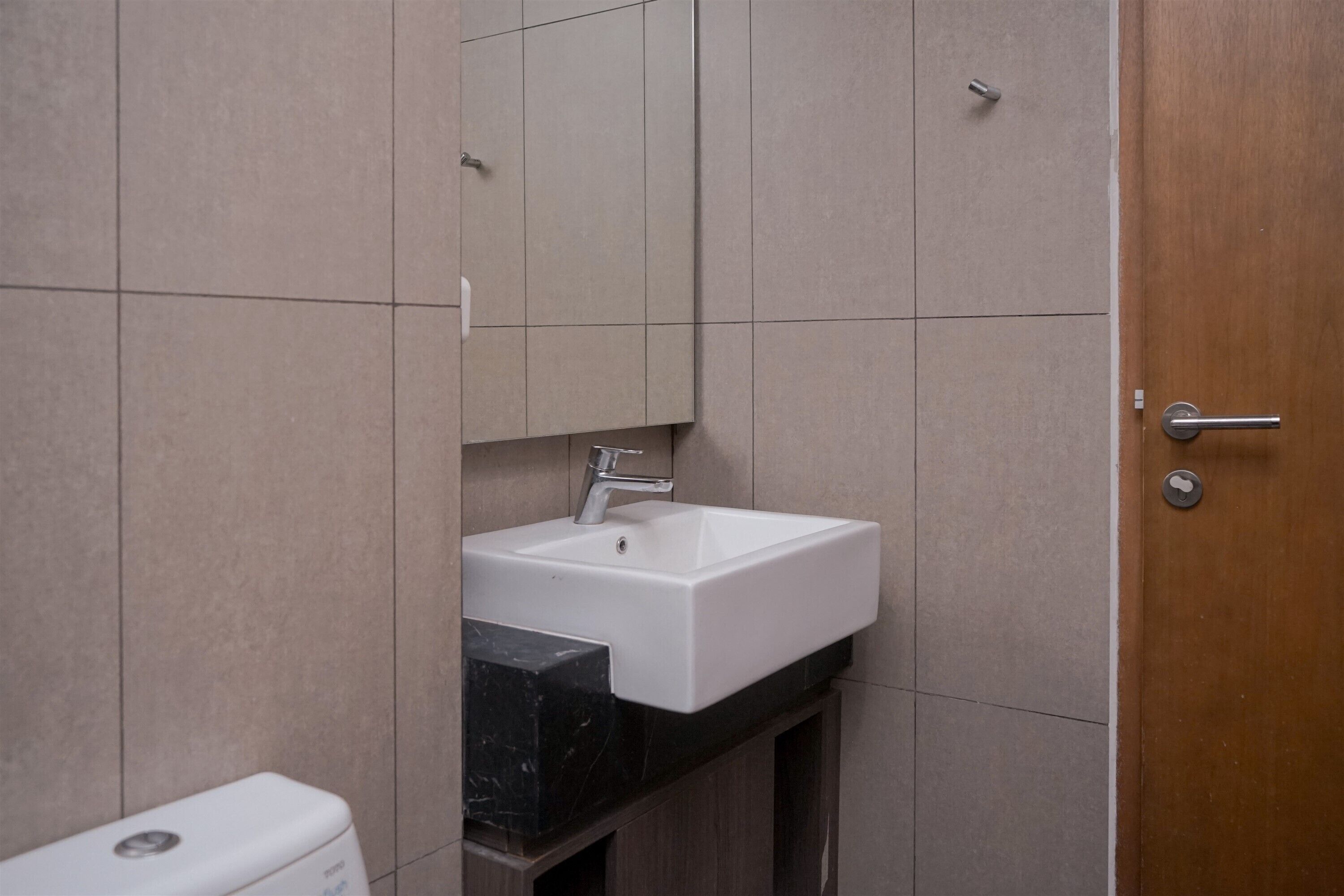 Une salle de bain avec un lavabo blanc, un miroir et des toilettes.