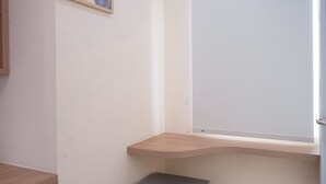A corner of a room with a wooden shelf, a small gray cabinet, and a white wall. - Best Furnished Studio (No Kitchen) Apartment At B Residence (Pagedangan)