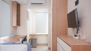 A hotel room with a bed, a desk, a TV, and a small kitchenette. - Best Furnished Studio (No Kitchen) Apartment At B Residence (Pagedangan)