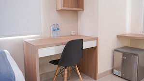A small office space with a wooden desk, a black chair, a water dispenser, and a small refrigerator. - Best Furnished Studio (No Kitchen) Apartment At B Residence (Pagedangan)