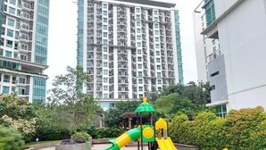 A playground with slides and swings, surrounded by greenery and residential buildings. - Good Location 2Br Apartment At Woodland Park Residence (Jakarta)