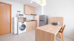 A compact kitchen with a washing machine, microwave, and refrigerator. - Good Location 2Br Apartment At Woodland Park Residence (Jakarta)