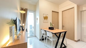 A modern kitchen with a wooden countertop, white chairs, and a dining table. There is a plant on the counter and a framed picture on the wall. - White Toned Style 2Br Tokyo Riverside Pik 2 Apartment (Teluknaga)