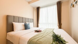 A hotel room with a bed, a headboard, curtains, and a window. - White Toned Style 2Br Tokyo Riverside Pik 2 Apartment (Teluknaga)