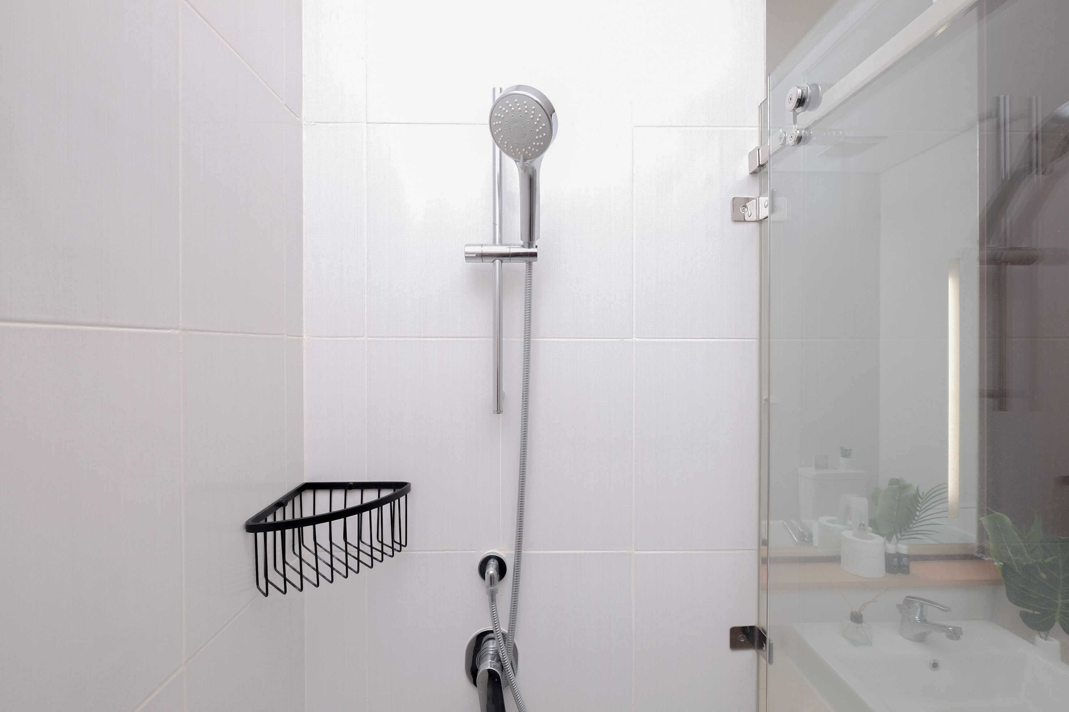 A modern bathroom with a glass shower enclosure, a black towel rack, and a visible sink area.