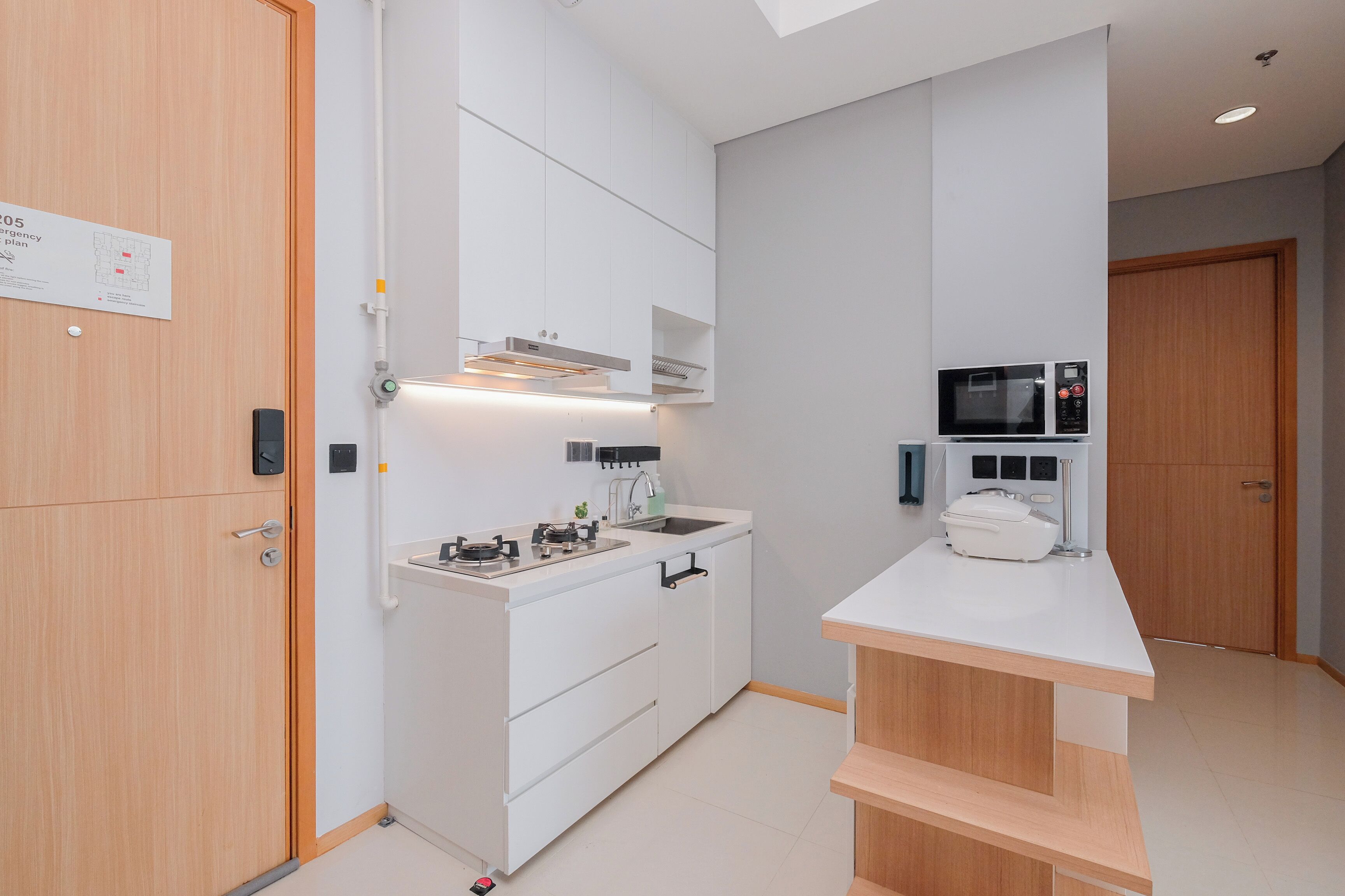 A modern kitchen with white cabinets, a built-in oven, and a microwave.