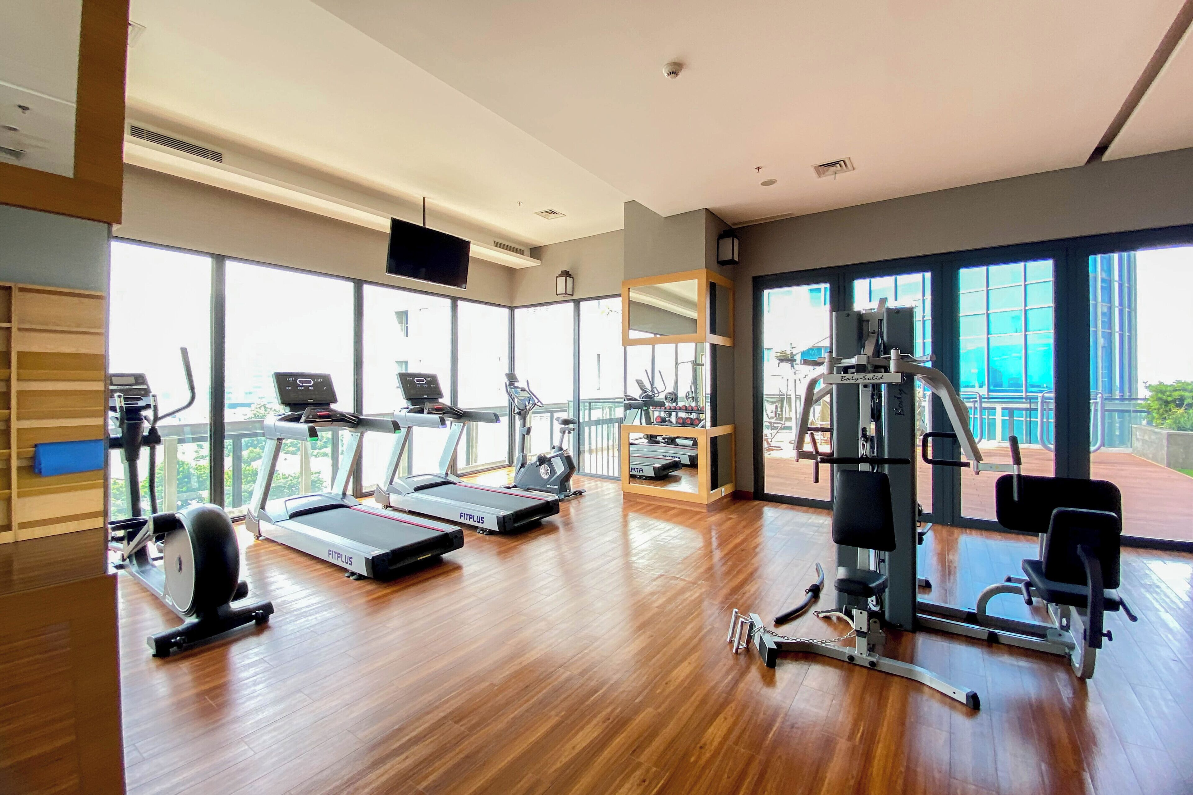 A modern gym with treadmills, elliptical machines, and weight equipment.