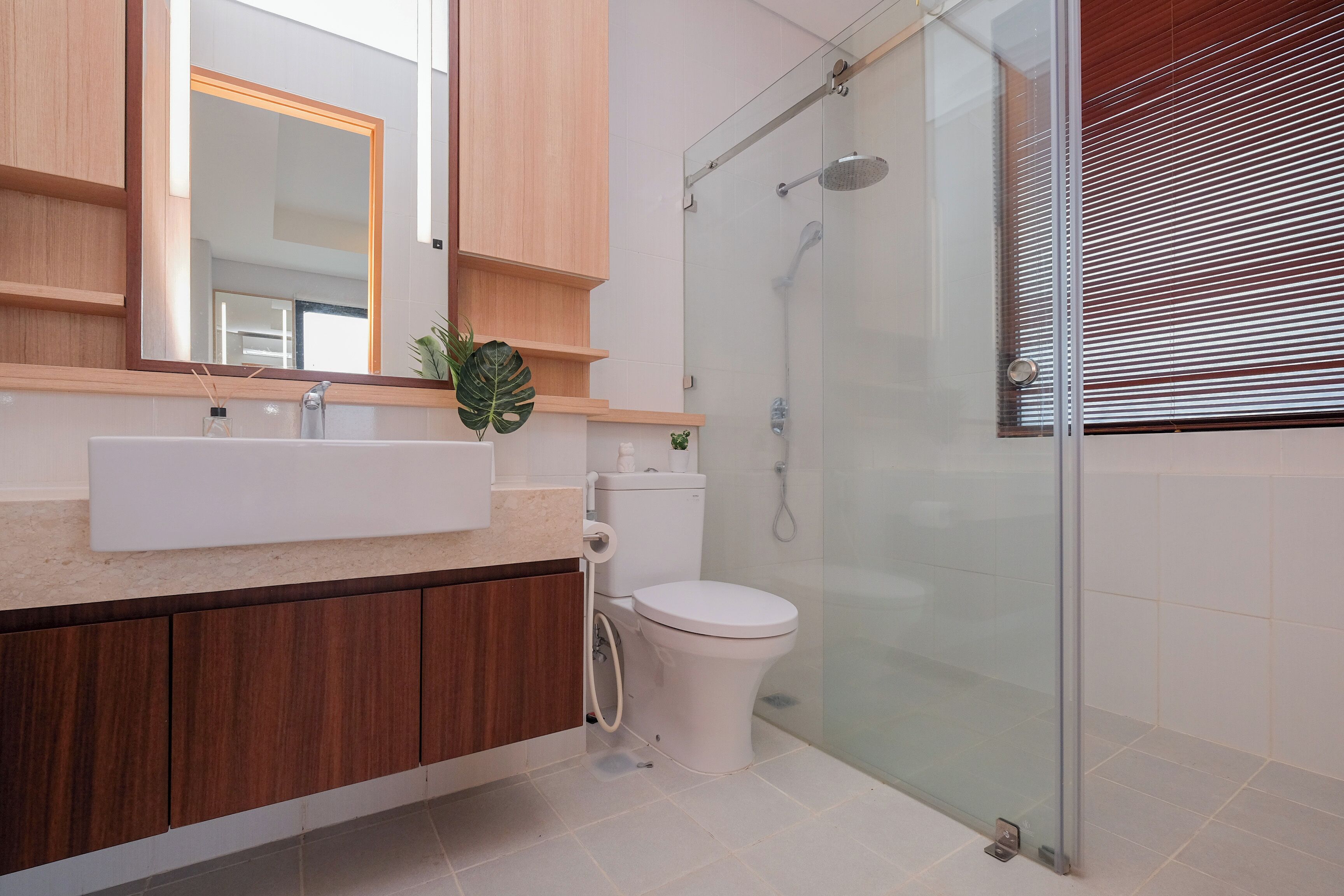 Un bany modern amb plat de dutxa envoltat de vidre, un lavabo blanc i un vàter.