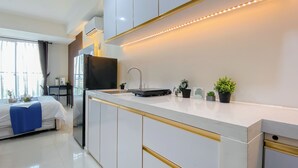 Een moderne keuken met witte kasten, een zwart aanrecht en gouden details.
