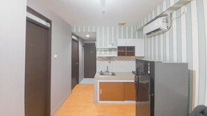 Una cocina compacta con refrigerador, lavamanos y una pequeña encimera.