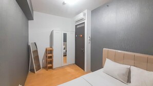 Un dormitorio con cama, armario, espejo y aire acondicionado.