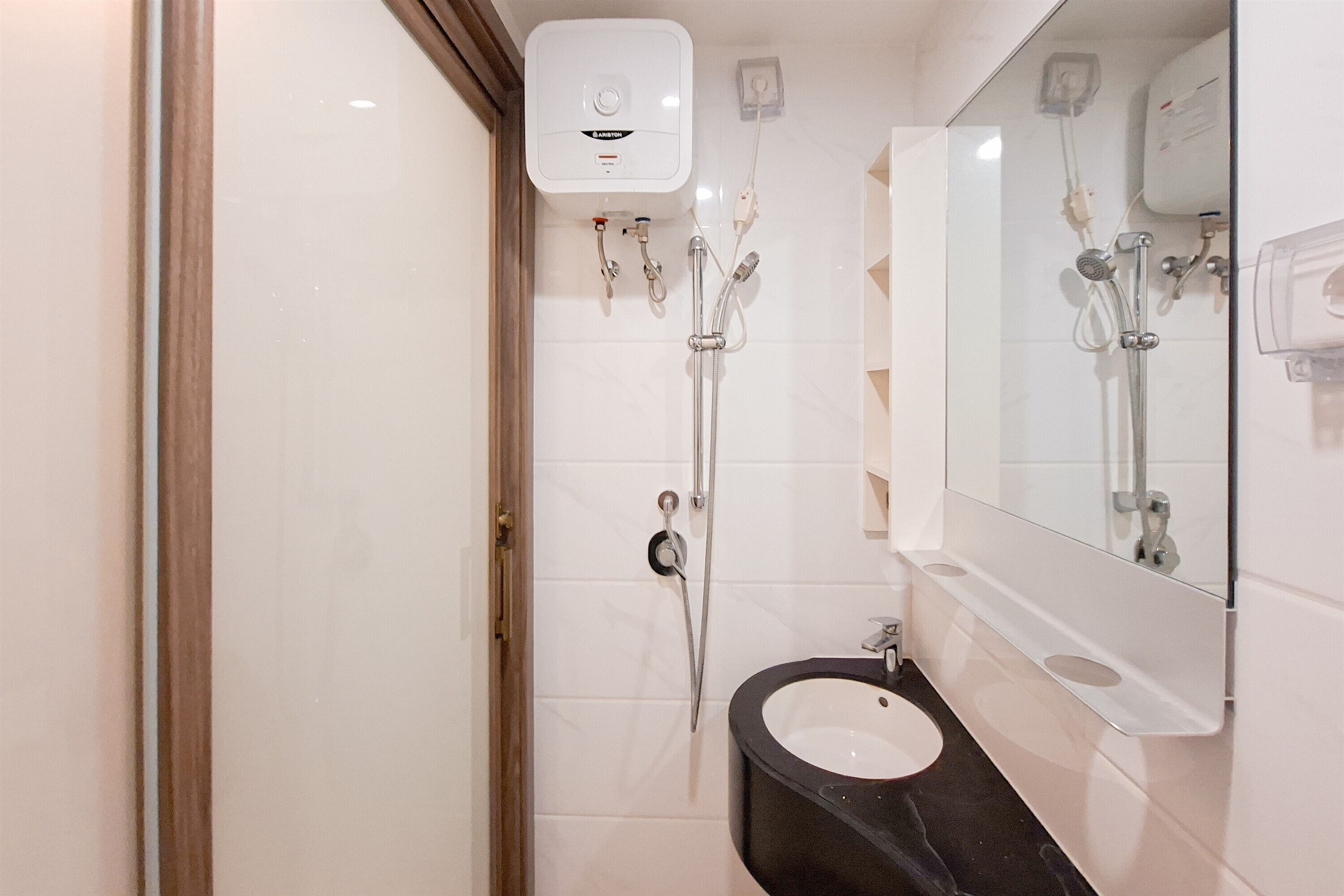 A modern bathroom with a glass shower enclosure, a black sink, and a large mirror.