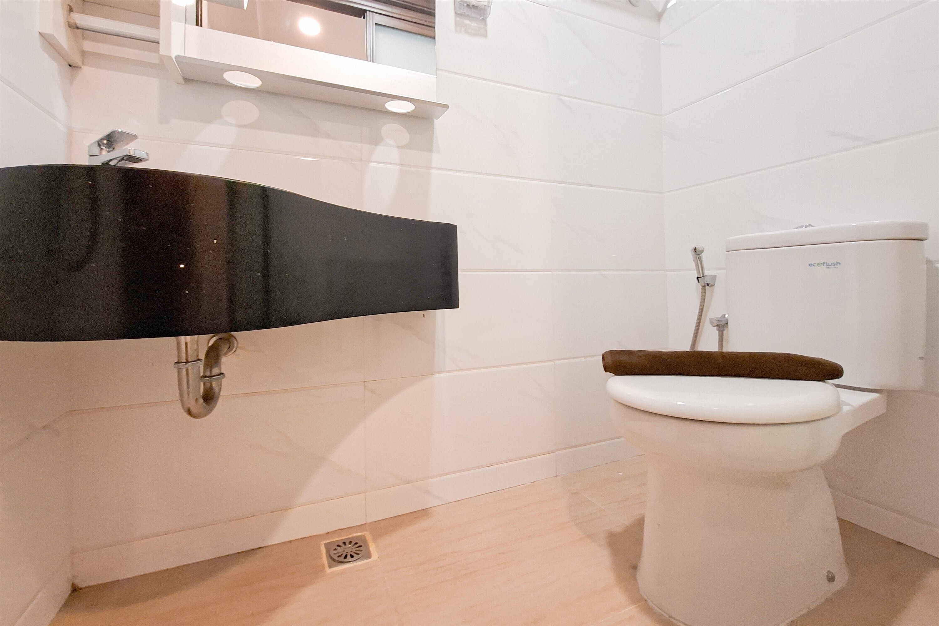 Un bagno con un lavandino nero, un water bianco e pareti piastrellate.