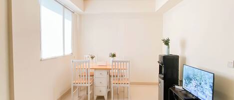 A compact living space with a dining area, a TV, and a small plant.