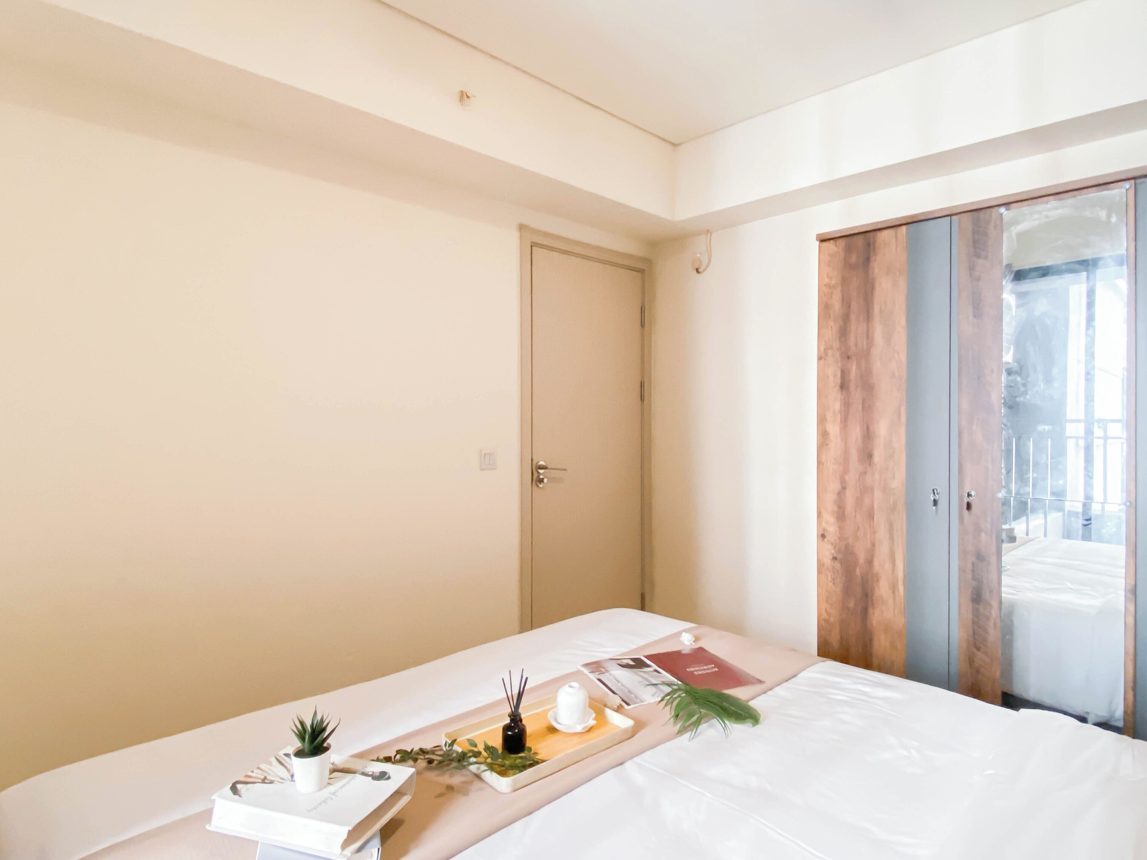 A modern bedroom with a bed, a bedside table with a tray, a small plant, and a door.