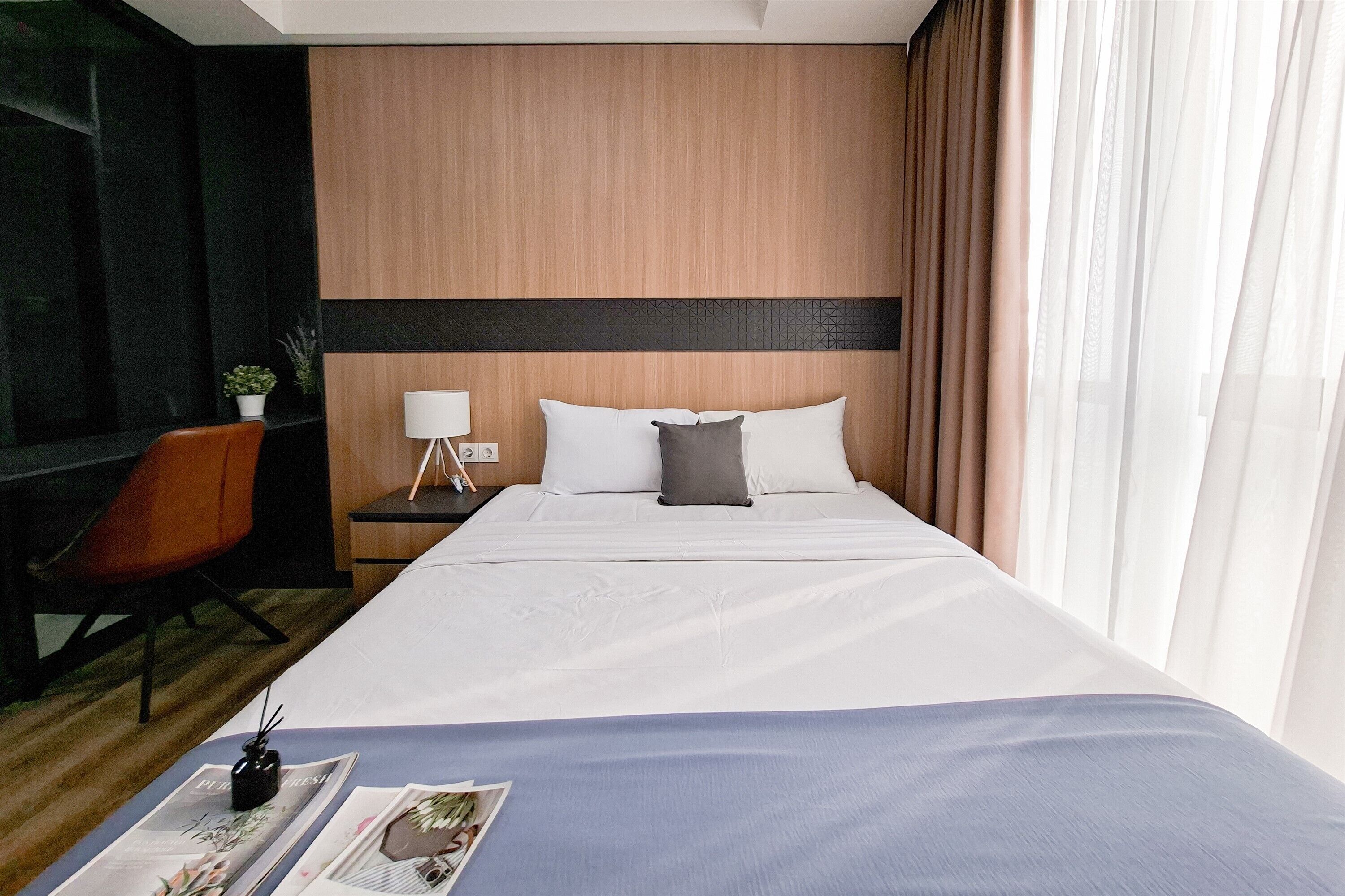 Una camera d'albergo con un letto, una scrivania, una sedia e una finestra con tende.