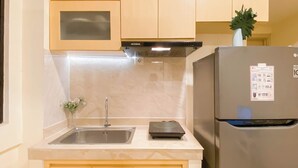 A kitchen with a stainless steel refrigerator, a built-in microwave, and a sink. - Modern Contemporary 2Br Apartment At Meikarta (Cikarang)