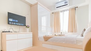Ein modernes Schlafzimmer mit Bett, Fernseher und Schreibtisch.