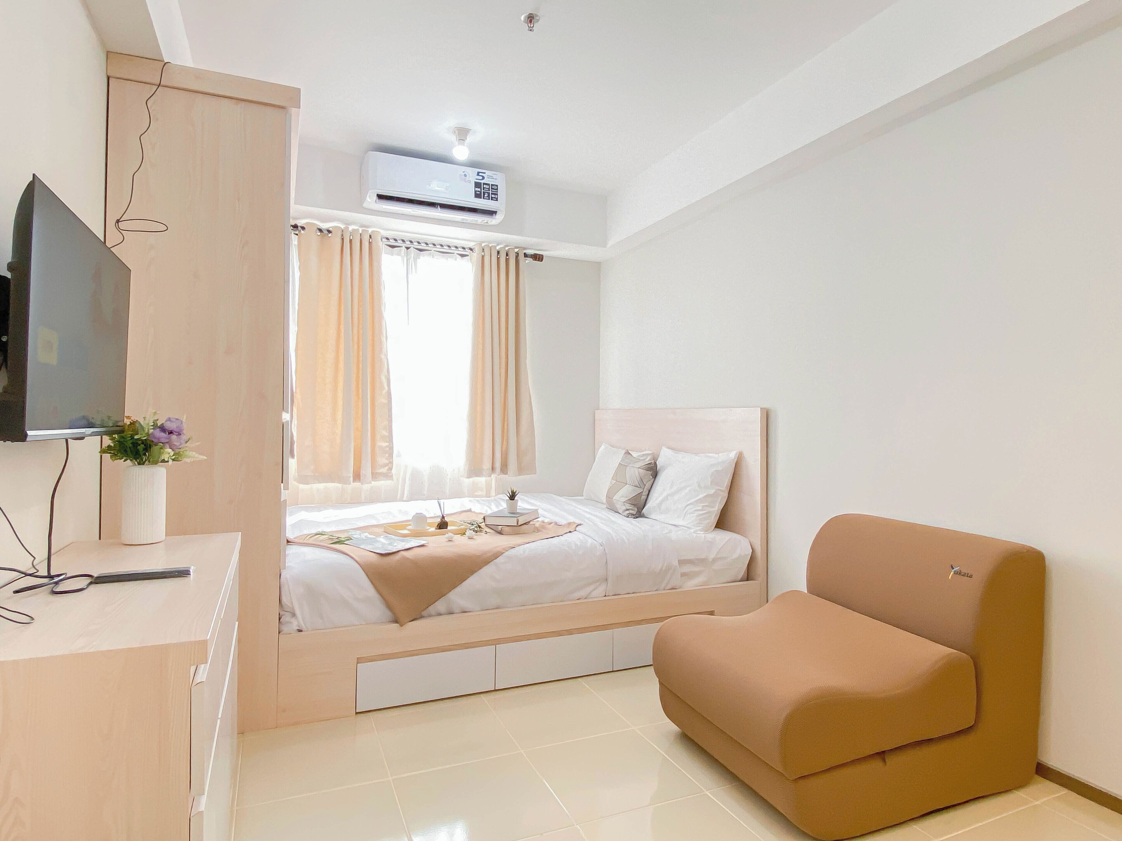 A modern bedroom with a bed, a TV, a desk, and a chair.