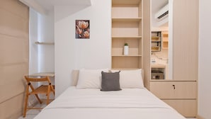 A bedroom with a bed, a chair, a desk, and built-in shelving. - Simple Style Studio Apartment (No Kitchen) At Tokyo Riverside Pik 2 (Teluknaga)