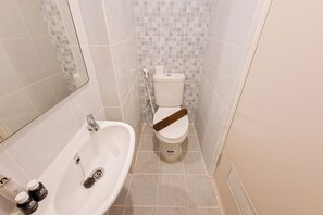 A bathroom with a white sink, toilet, and mirror. - Simple Style Studio Apartment (No Kitchen) At Tokyo Riverside Pik 2 (Teluknaga)