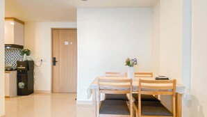A dining area with a table and chairs, a water dispenser, and a door in the background. - 3Br Apartment Near Dian Harapan School At Meikarta (Cikarang)